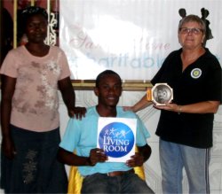 Seen behind Jenny 
                  the Sandy Lane Charitable Trust banner as well as the Living Room logo held by Pastor Nicholas our Port of Prince Representative