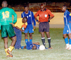 Barbados striker Rondell Vaughan (on ground) being attended by a paramedic druing in last Sunday’s match against Guyana. 
