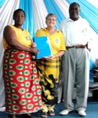 Bishop and his wife receiving their Zambia Master Copies of the KIMI curriculum, being presented by Jenny Tryhane their KIMI Leadership trainer. 